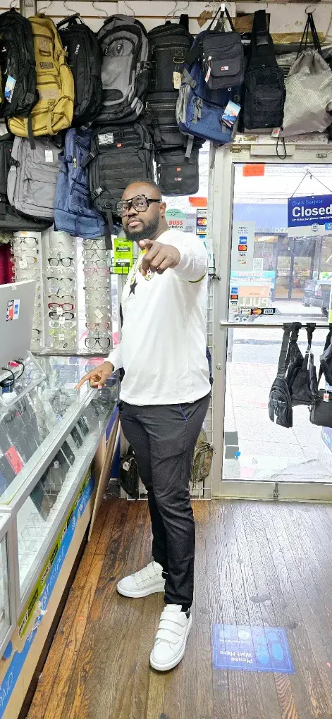 Customer pointing inside Maxworld Tech Store next to backpacks and eyewear