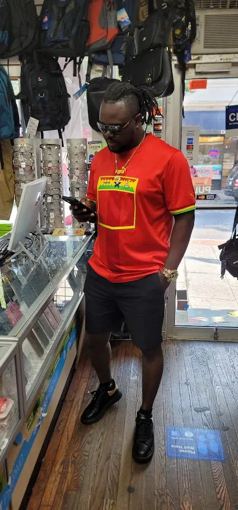 Customer in a red jersey checking his phone at the counter